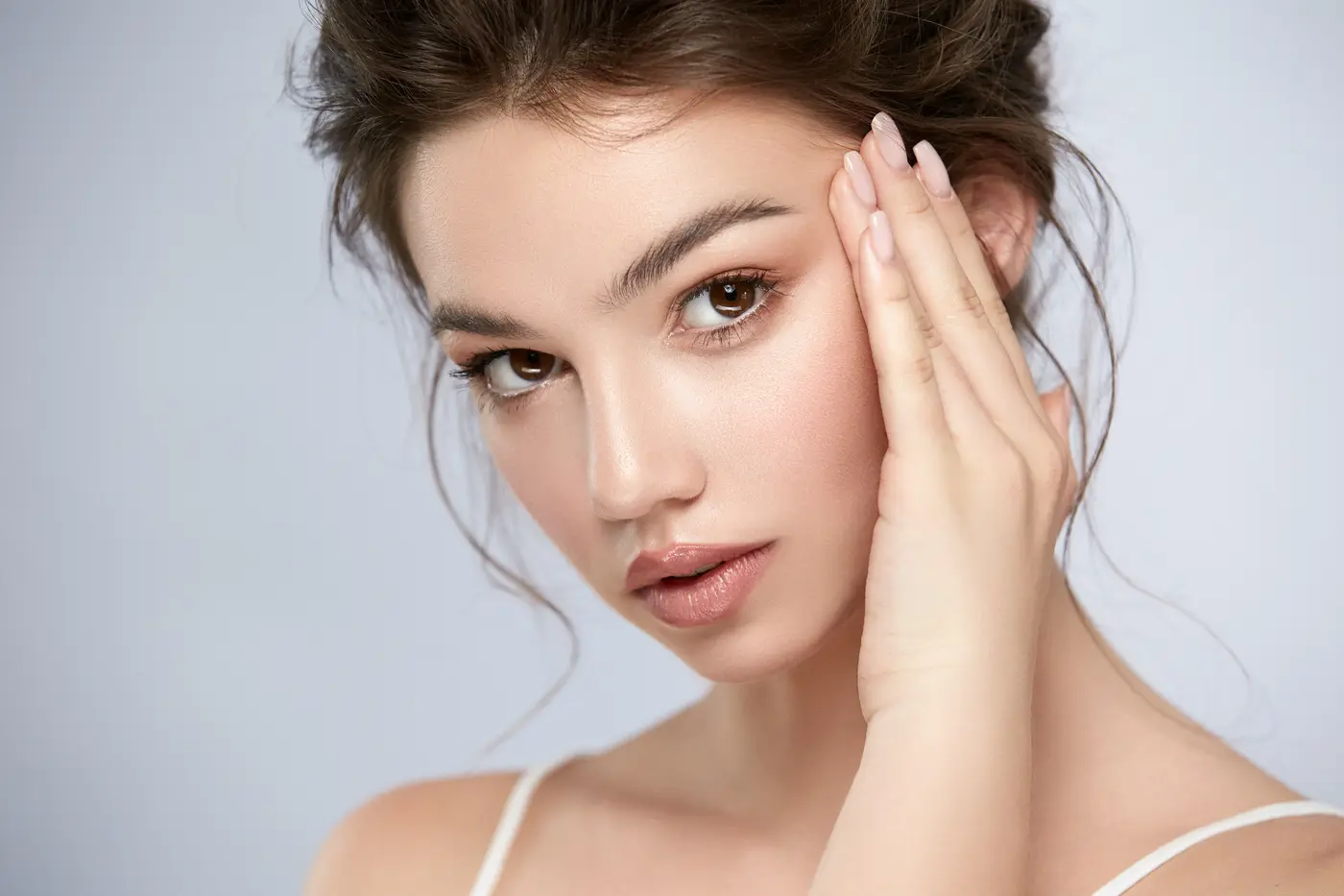 Woman with flawless skin touching face, highlighting youthful complexion.